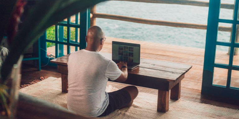 imagem de pessoa trabalhando remotamente em um local com vista para o mar